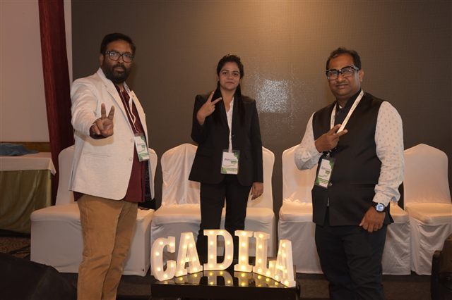 Three delegates posing beside the marquee letters